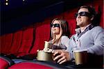 Attractive young couple in 3D glasses watching movies in cinema