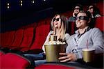 Laughing young people in 3D glasses watching a movie at the cinema