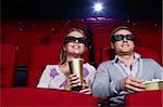 Attractive couple in 3D glasses watching movies in cinema