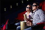 Young couple watching a movie in 3D glasses in cinema