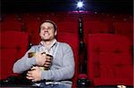 Attractive young man with popcorn watching a movie at the cinema