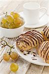 mini chocolate croissants, grapes and coffee cup on a rustic wood table