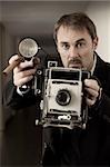 Photo of a retro 1940's style photographer taking a photo with an old 4x6 camera.  Desaturated and toned for retro feel.