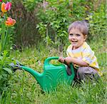 Cute little boy watering the flowers in the garden