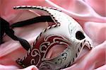 Carnival mask over pink satin, shallow depth of field