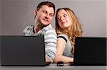 man and woman is sitting together on gray background with laptops