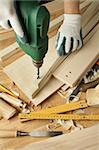 Wooden workshop table with tools. Man's arms drill plank.