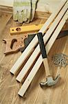 Hammer, saw, level, gloves, planks and nails on wooden floor