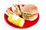 Healthy turkey burger, on a whole grain bun, with baked potato wedges and corn on the cob.  Isolated with clipping path.