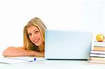 Sitting at table smiling teen girl looking out from laptop