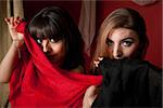 Two gorgeous belly dancers partially cover their face with a piece of cloth