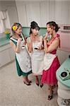 Three women gossiping in a kitchen while smoking cigarettes