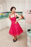 Happy middle-aged woman with hands on hips in retro-styled kitchen scene