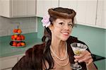 Caucasian woman wearing veil and mink coat enjoying martini in kitchen