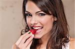 Portrait of pretty young woman eating a strawberry