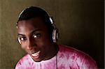 Young smiling Black man in pink tie-dye shirt with large headphones