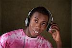 Handsome Black man in pink tie-dye shirt removes part of his headphones
