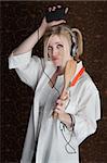 Beautiful Caucasian woman listening to music on headphones from player and holding a spatula