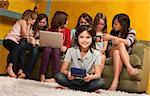 Smiling little girl playing video game on portable console with her friends