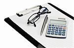 Angled note pad, pen, glasses and pocket calculator on a white background