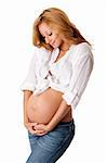 Beautiful new happy mother in late pregnancy wearing fashion jeans and white, looking at tummy holding belly, isolated.