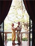 senior caucasian couple on vacation, dancing on terrace in hotel. Vertical shape, full length, side view