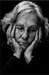 In a dark place: Dramatic exagerated low key portrait of an elderly woman looking very depressed and alone.