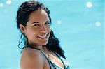 Beautiful happy young hispanic woman smiling and relaxing near resort swimming pool. Horizontal shape, side view, copy space