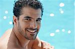 Handsome happy young hispanic man smiling and relaxing near hotel pool. Horizontal shape, head and shoulders, copy space
