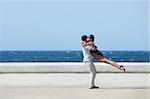 euphoric young couple meeting and hugging near the sea. Horizontal shape, side view, copy space