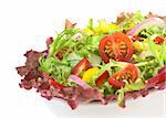 Fresh mixed salad from red-leaf lettuce, curly endive (frisee), cherry tomato, red onion, cucumber and red and yellow bell pepper in white bowl on white (Selective Focus, Focus on the cherry tomato half)