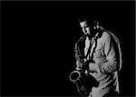 Young handsome man playing music on saxophone. black background