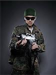 Young soldier in camouflage and ammunition with a gun. studio shot