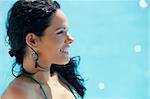 Beautiful happy young hispanic woman smiling and relaxing near resort swimming pool. Horizontal shape, side view, copy space
