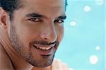 Handsome happy young hispanic man smiling and relaxing near hotel pool. Horizontal shape, headshot, copy space