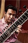 Handsome Indian man in traditional attire plays a Sitar