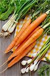 Carrot, green onion, young garlic and herbs on an old wooden board.