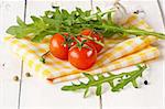 Tomatoes, arugula, garlic on a yellow napkin.