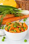 Carrot salad with green peas in a white ceramic bowl.