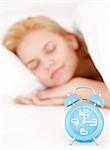 Lovely young woman sleeping in the bed, with a blue alarm clock in the front