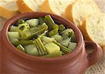 Green bean and potato hotpot in rustic bowl with baguette slices around (Selective Focus, Focus on the front of the hotpot)