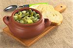 Green bean and potato hotpot in rustic bowl with baguette slices on wooden board and spoon in the back set up on jute (Selective Focus, Focus on the first half of the hotpot)