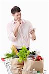 A thoughtful man with a cart with food on a white background