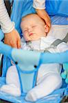 Mother's hand stroking  head sleeping  in stroller baby girl