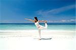 Woman practising Yoga (Warrior Position) on the beach.