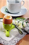 Brown soft boiled egg in the eggcup on a linen napkin.