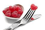 Red heart shaped jelly sweets with knife and fork on white background