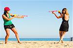 Girls with water pistols fooling around on the beach