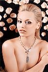 glamour portrait of a young blond girl with petals all around and a jewellery necklace