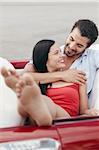 boyfriend and girlfriend lying inside vintage convertible car and hugging. Vertical shape, front view, copy space